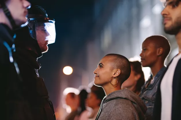Demonstrant*innen stehen Gesicht zu Gesicht vor Polizist*innen auf einer Demonstration
