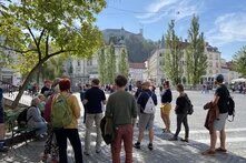 Die Reisegruppe steht auf einem zentralen Platz in Ljubljana und hört dem Reiseleiter zu.