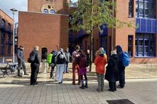 Foto vom Stadtrundgang in Bremerhaven, ca. 15 Personen stehen im Kreis vor einem alten Backsteingebäude der Hochschule Bremerhaven