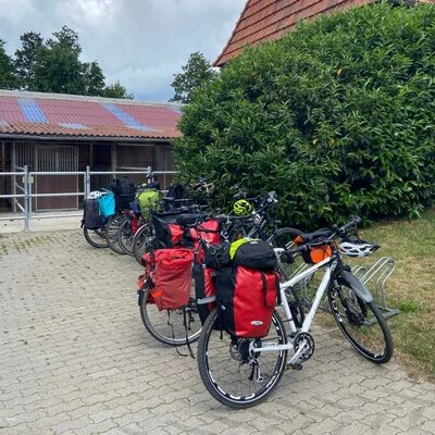 Geparkte Fahrräder mit Gepäck stehen auf einem Bauernhof neben einem Stall