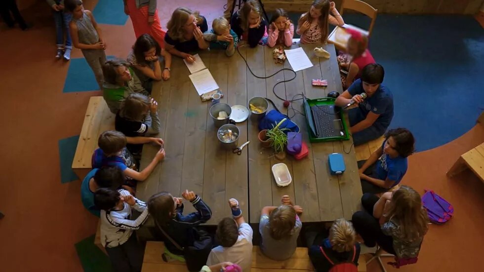 Kinder sitzen im Kreis um einen Tisch