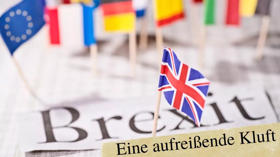 Kleine europäische Länderfahnen, in der Mitte die EU Fahne und vorne die Flagge Großbritanniens. Darunter steht "Brexit. Eine aufreißende Kluft"