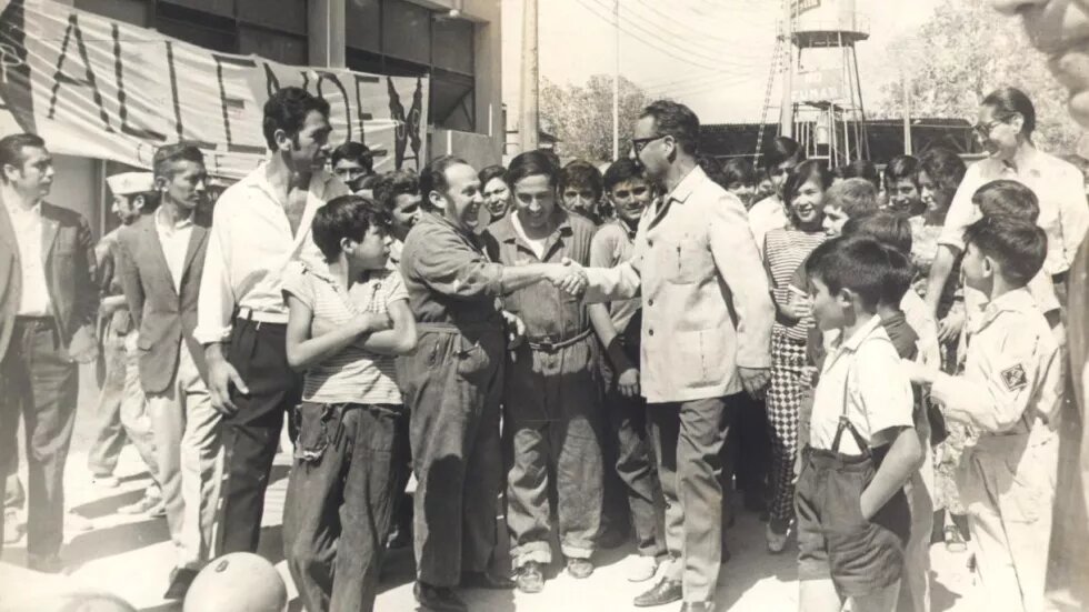 Ein schwarz-weiß-Bild des chilenischen Präsidents Salvador Allende, wie er in der Öffentlichkeit Hände schüttelt.